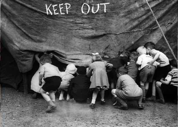 Photo noir et blanc : enfants regardent en douce sous une tente (de cirque, cinéma ?)