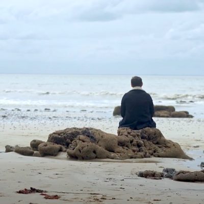 Un homme de dos assis sur la plage