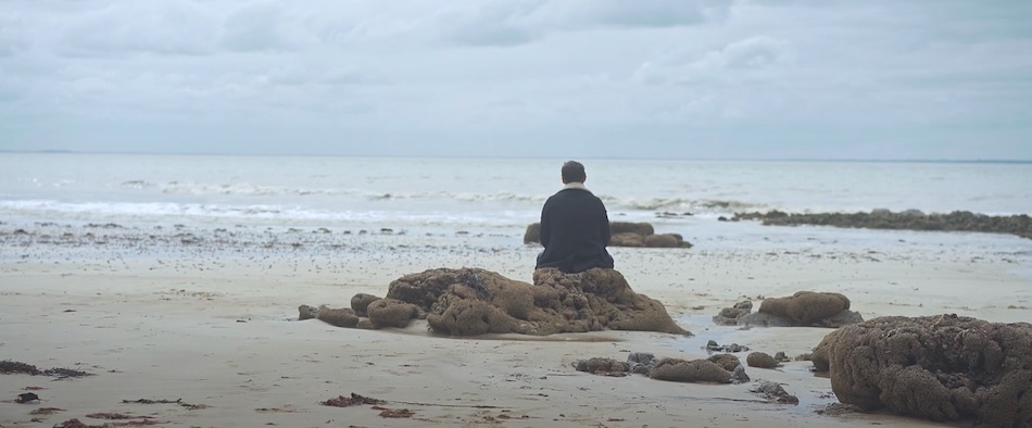 Un homme de dos assis sur la plage